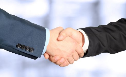 The firm handshake between two colleagues in office. Close-up image of a firm handshake between two colleagues in office.